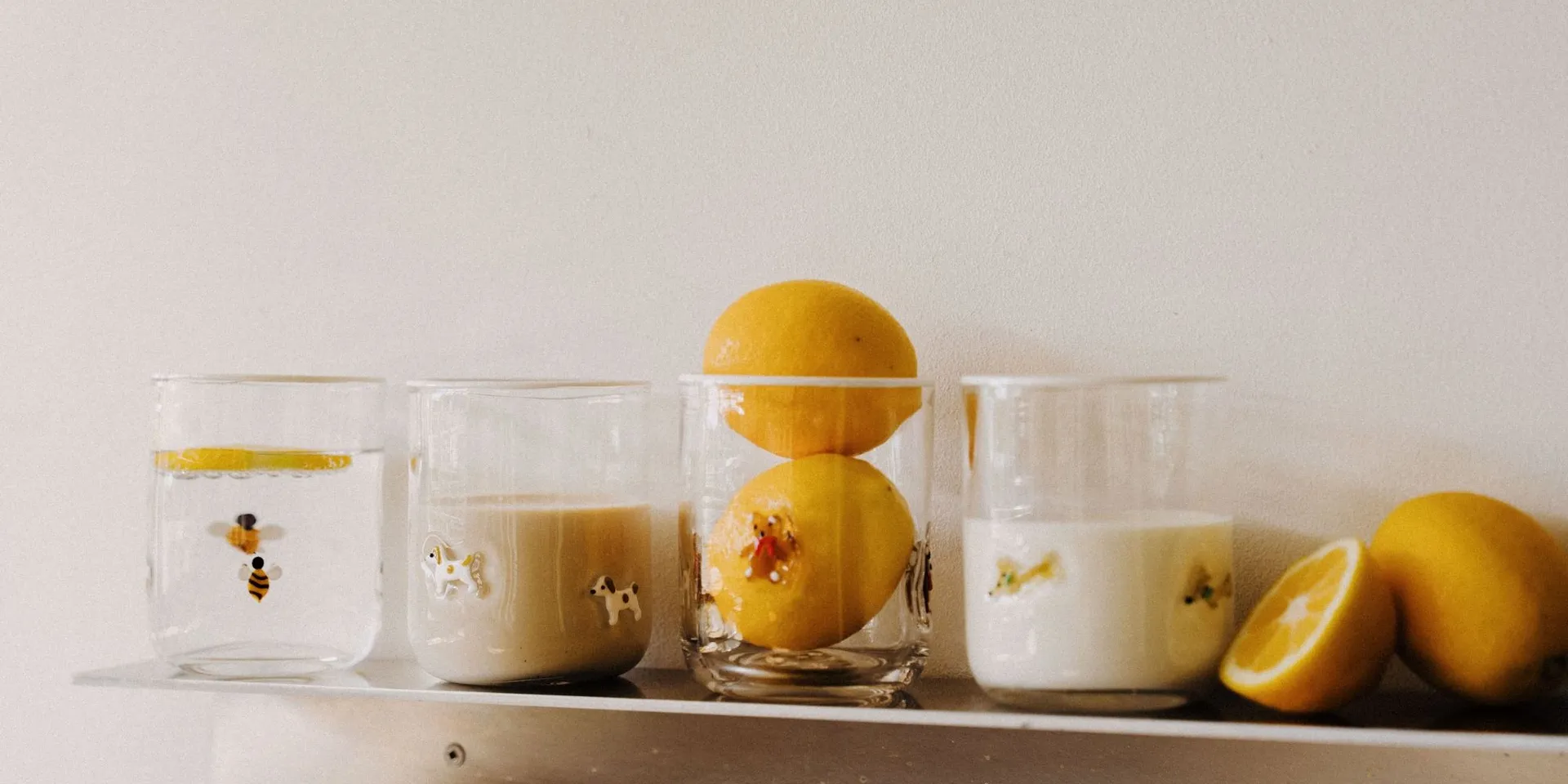 Bee, Pup, Teddy and Dachshund Icon Cups lined up on a steel shelf with fresh lemons